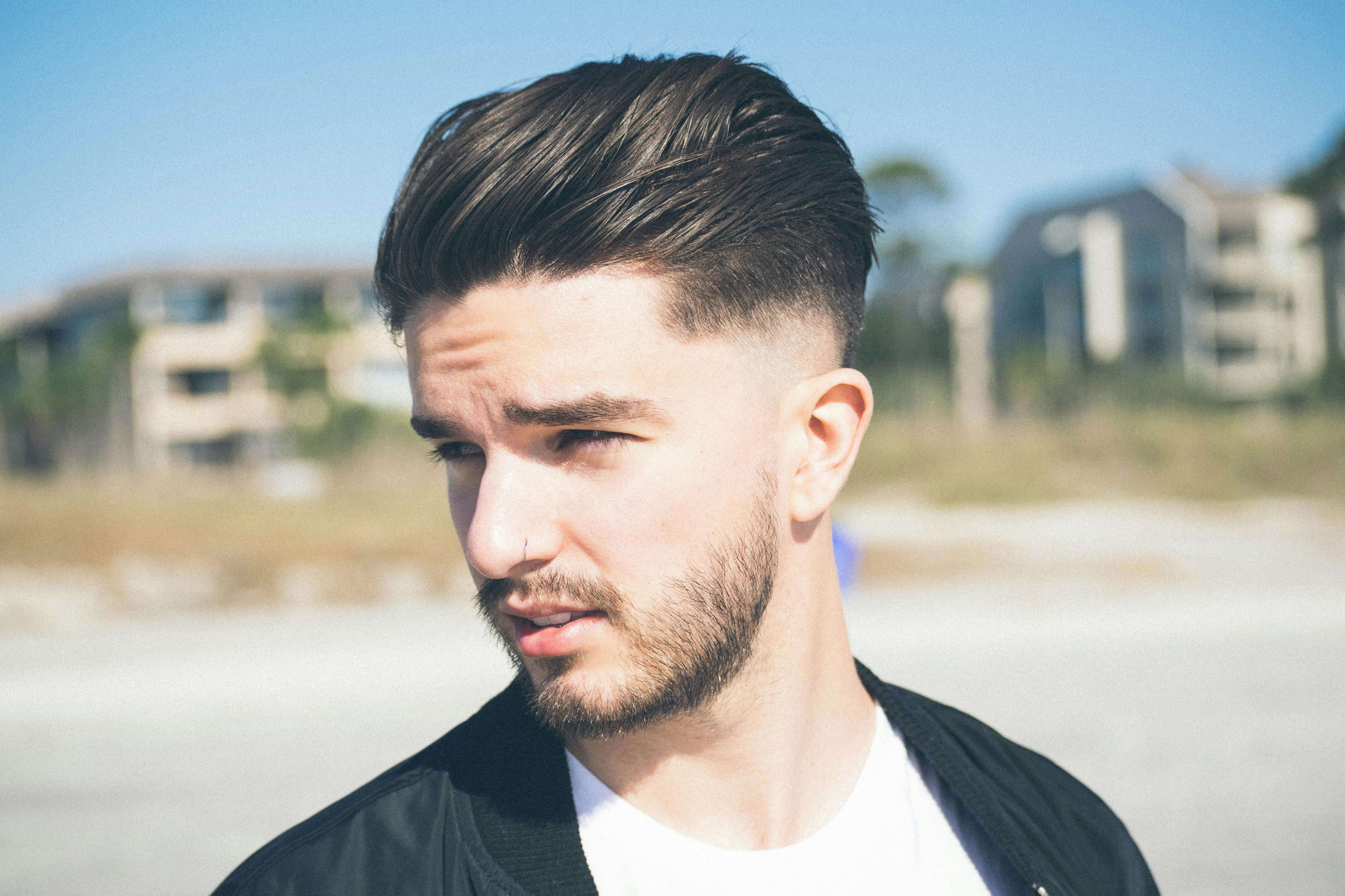 A man with styled hair usin ghair pomade.